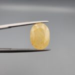 Official Galaxy Gemological Institute (GGI) Gemstone Report for a 6.25-carat Natural Yellow Sapphire. The certificate lists report number KHI260609001 and displays a digital product image of the loose, oval-cut semi-transparent stone resting on a white reflective surface, emphasizing its bright, sun-kissed yellow tone and prominent mixed faceting architecture.