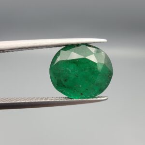 ​A premium 4.45-carat natural Pakistani Emerald gemstone resting flat on a white textured leather insert inside a display box. The loose, earth-mined beryl gem is precision cut into an elegant, well-proportioned oval shape, exhibiting an incredibly rich, deep grass-green color with a classic velvety internal glow.