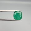 ​A premium 3.84-carat natural Pakistani Emerald gemstone resting flat on a white textured leather insert inside a display box. The loose, earth-mined beryl gem is precision cut into an elegant, well-proportioned cushion shape, exhibiting an incredibly rich, deep grass-green color with unique internal clouds and beautiful inclusion patterns that catch the light.