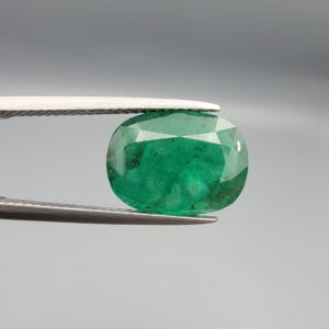 A premium 4.28-carat natural Pakistani Emerald gemstone resting flat on a white textured presentation insert inside a black display box. The loose, earth-mined beryl gem is precision cut into an elegant, well-proportioned oval shape, showcasing a deeply saturated, classic grass-green body color with an excellent face-up table spread.