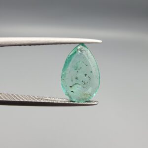 ​A 2.06-carat natural Colombian Emerald gemstone held vertically in professional metal gemstone tweezers against a smooth gray studio background. The loose gem is fashioned into a graceful pear shape, displaying a highly authentic, transparent mint-to-forest green core filled with dense, raw internal mountain fissures, natural inclusions, and soft organic mineral cracks.