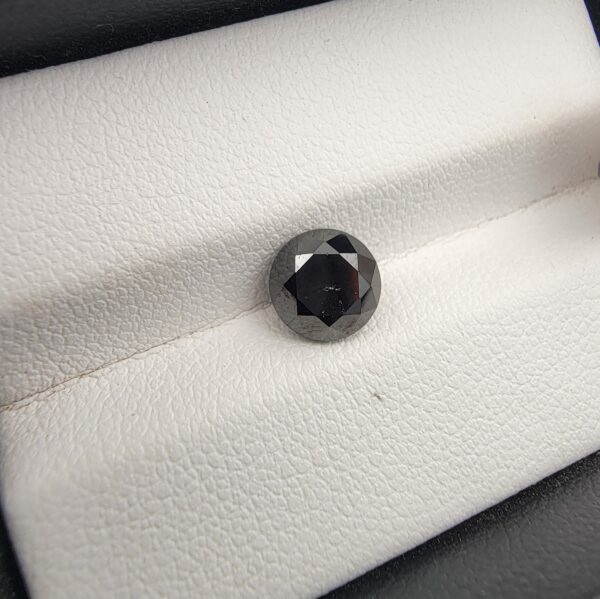 An official authenticity identification card from the Jaipur Gemological Lab for Specimen No. 1773046, certifying a 1.70-carat Natural Black Diamond. The lab certificate provides full technical metrics, showing measurements of 6.74 x 5.30 mm, a round brilliant cut, a Mohs hardness of 10, and includes a small photographic insert of the round faceted opaque black diamond.