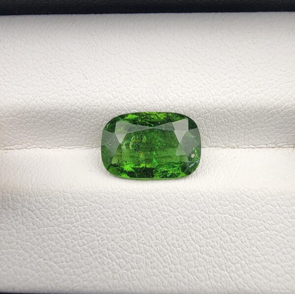 A premium, high-brilliance 2.97-carat natural Vivid Green Tourmaline gemstone from Madagascar resting elegantly inside a white leather-textured luxury display box. The loose gem showcases a masterfully faceted cushion cut with excellent edge symmetry, displaying an intensely vibrant, rich green color saturation paired with breathtaking internal sparkle and light performance.
