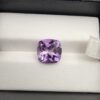 ​A high-clarity 4.21-carat natural Brazilian Amethyst gemstone beautifully presented in a luxury white-cushioned black leatherette display box. The loose gem showcases a brilliant cushion cut with softly rounded rectangular edges, displaying a uniform, bright violet-purple color profile with magnificent internal light performance and sharp facet symmetry.