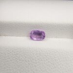 A rare, high-clarity 0.80-carat natural Ceylon Purple Sapphire gemstone nestled securely in a luxury white-cushioned black display box. The loose gem showcases an elegant faceted cushion cut with softly rounded edges, displaying an intensely saturated deep violet-purple to royal purple body color with outstanding internal light refraction and pristine facet symmetry.