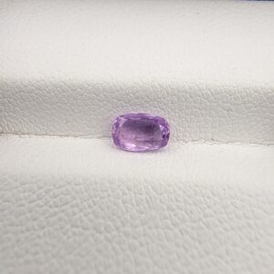 A rare, high-clarity 0.80-carat natural Ceylon Purple Sapphire gemstone nestled securely in a luxury white-cushioned black display box. The loose gem showcases an elegant faceted cushion cut with softly rounded edges, displaying an intensely saturated deep violet-purple to royal purple body color with outstanding internal light refraction and pristine facet symmetry.