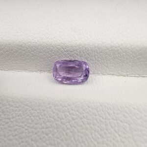 ​A premium, high-clarity 1.06-carat natural Ceylon Purple Sapphire gemstone nestled securely in a luxury white-cushioned black display box. The loose gem showcases an elegant faceted cushion cut with beautifully soft edges, displaying an intensely saturated, deep royal purple and vibrant violet body color with pristine facet symmetry and outstanding internal light reflection.