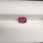 ​A rare, high-clarity 0.97-carat natural Ceylon Purplish Pink Sapphire gemstone nestled securely in a luxury white-cushioned black display box. The loose gem showcases an elegant faceted cushion cut with beautifully soft edges, displaying an intensely saturated, exotic purplish pink body color with pristine facet symmetry and outstanding internal light reflection.