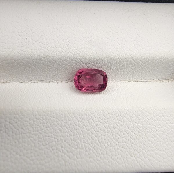 ​A rare, high-clarity 0.97-carat natural Ceylon Purplish Pink Sapphire gemstone nestled securely in a luxury white-cushioned black display box. The loose gem showcases an elegant faceted cushion cut with beautifully soft edges, displaying an intensely saturated, exotic purplish pink body color with pristine facet symmetry and outstanding internal light reflection.
