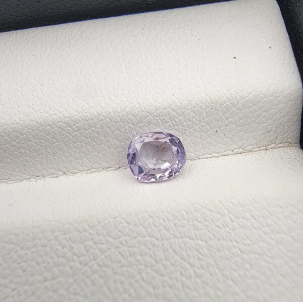 A premium, high-clarity 0.76-carat natural Ceylon Light Purple Sapphire gemstone nestled securely in a luxury white-cushioned black display box. The loose gem showcases an elegant faceted cushion cut with step-cut crown facets, displaying a delicate, brightly saturated light violet-purple body color with excellent internal light transparency and pristine facet symmetry.