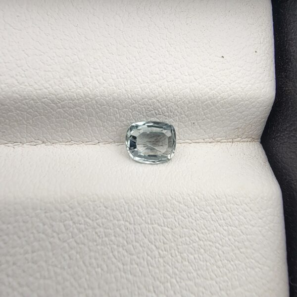 A rare, high-clarity 0.66-carat natural Ceylon Light Green Sapphire gemstone nestled securely in a luxury white-cushioned display box. The loose gem showcases an elegant faceted cushion cut, displaying a delicate, brightly saturated pastel mint green body color with outstanding internal light refraction and pristine facet symmetry.