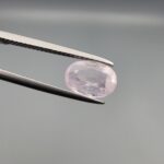 A premium, high-clarity 1.78-carat natural Ceylon Light Pink Sapphire gemstone held securely in metal tweezers against a clean grey background. The loose gem showcases an elegant faceted oval cut with beautifully balanced proportions, displaying a delicate, brightly translucent pastel pink body color with pristine facet symmetry, zero enhancements, and exceptional internal light reflection.
