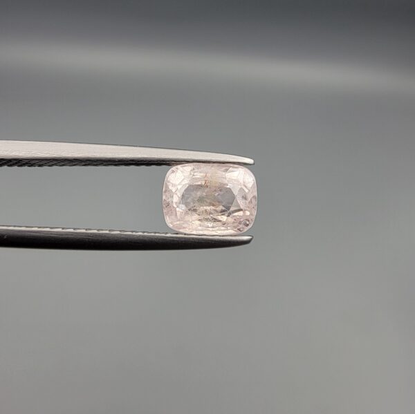 a premium, high-translucency 1.81-carat natural Ceylon Light Pink Sapphire gemstone is held securely in metal tweezers against a clean, neutral grey background. The loose gem showcases an elegant faceted cushion cut with beautifully sharp facet junctions, displaying a delicate, softly translucent pastel pink body color with pristine facet symmetry, zero enhancements, and fine internal natural inclusions that verify its entirely untreated origin.