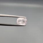 A premium, high-translucency 1.72-carat natural Ceylon Light Pink Sapphire gemstone is held securely in metal tweezers against a clean, neutral grey background. The loose gem showcases an elegant faceted cushion cut with beautifully sharp facet junctions, displaying a delicate, softly translucent pastel pink body color with pristine facet symmetry, zero enhancements, and fine internal natural inclusions that verify its entirely untreated origin.
