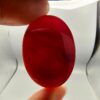 A giant, masterfully polished 85.42-carat natural oval Yemeni Carnelian Agate cabochon is held between fingers against a grey background, displaying a flawless mirror-like gloss and a rich, deep liver-brown (Kaleji) color. In a secondary view under dark conditions, the exact same gemstone is illuminated by a torch light from behind, revealing a brilliant, glowing translucent red (Laal) interior adorned with delicate, fine natural agate structural banding.