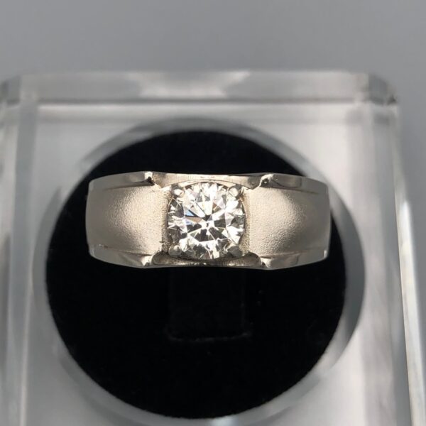 ​A luxury men's or unisex ring crafted from pure sterling silver, featuring a substantial 1.30-carat round brilliant cut natural diamond as the central focal point. The diamond is held securely by four robust prongs within a thick, textured silver band that combines a brushed metal finish with polished borders, all presented beautifully within a black-cushioned display case.
