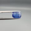 a premium, beautifully faceted 2.96-carat natural Blue Sapphire gemstone is held securely in metal tweezers against a clean, neutral grey background. The loose corundum gem showcases an expert cushion cut with a well-proportioned table, displaying a rich, vibrant blue color with fine, genuine internal crystal characteristics and natural silk inclusions that verify its authentic earth-mined origin.