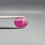 ​A premium, beautifully faceted 4.00-carat natural Ruby gemstone is held securely in metal tweezers against a clean, neutral grey background. The loose corundum gem showcases an expert oval cut with a well-proportioned table, displaying a rich pink color with fine, genuine internal crystal characteristics and natural silk inclusions that verify its rare, unheated earth-mined origin.
