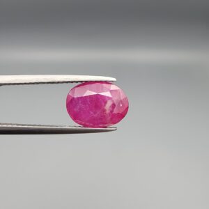 ​A premium, beautifully faceted 4.00-carat natural Ruby gemstone is held securely in metal tweezers against a clean, neutral grey background. The loose corundum gem showcases an expert oval cut with a well-proportioned table, displaying a rich pink color with fine, genuine internal crystal characteristics and natural silk inclusions that verify its rare, unheated earth-mined origin.
