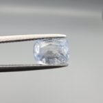 A premium, beautifully faceted 2.37-carat natural Blue Sapphire gemstone rests inside a white leatherette display box. The loose cushion-cut corundum gem displays a soft, icy light-blue tone with fine internal silk and genuine crystal characteristics that serve as an indisputable signature of its unheated, earth-mined origin.