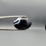 "Natural Black Banded Agate Sulemani Aqeeq oval cabochon gemstone 15.35 carat held in tweezers showing white banding"