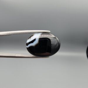 "Natural Black Banded Agate Sulemani Aqeeq oval cabochon gemstone 15.35 carat held in tweezers showing white banding"