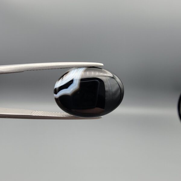 "Natural Black Banded Agate Sulemani Aqeeq oval cabochon gemstone 15.35 carat held in tweezers showing white banding"