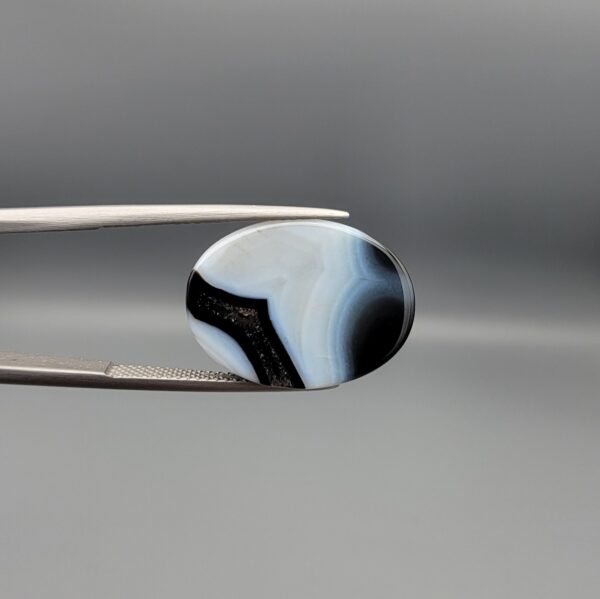 "Natural Black Banded Agate Sulemani Aqeeq oval cabochon gemstone 15.35 carat held in tweezers showing white banding"