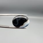 "Natural Black Banded Sulemani Aqeeq Agate oval cabochon gemstone 14.03 carat with horizontal white and brown wave band held in tweezers"