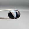 "Natural Black Banded Sulemani Aqeeq Agate oval cabochon gemstone 15.15 carat with diagonal white and brown swirl band held in tweezers"