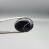 "Natural Black Banded Sulemani Aqeeq Agate oval cabochon gemstone 15.33 carat with thin white thread line held in tweezers"