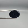 "Natural Black Banded Sulemani Aqeeq Agate oval cabochon gemstone 15.33 carat with thin white thread line held in tweezers"