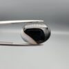 "Natural Black Banded Sulemani Aqeeq Agate oval cabochon gemstone 14.14 carat with diagonal white and brown corner band held in tweezers"