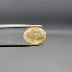 "Natural unheated Yellow Sapphire Pukhraj gemstone 2.75 carat oval cut from Sri Lanka Ceylon held in tweezers showing natural silk inclusions"