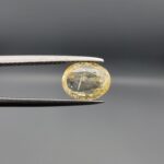 "Natural unheated Yellow Sapphire Pukhraj gemstone 2.05 carat oval cut from Sri Lanka Ceylon held in tweezers showing visible natural crystal inclusion"