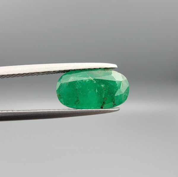 "Natural Emerald Panna Zamrud gemstone 2.35 carat oval cut from Swat Valley Pakistan held in tweezers showing rich green color and natural jardin inclusions"