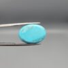 "Natural Razaki Feroza Turquoise gemstone 20.67 carat oval cabochon from Iran, front smooth sky-blue face and back natural matrix view, held in tweezers"