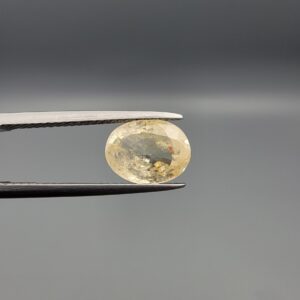 "Natural unheated Yellow Sapphire Pukhraj gemstone 2.88 carat oval cut from Sri Lanka Ceylon held in tweezers showing pale golden color and natural feather inclusions"