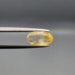 "Natural unheated Yellow Sapphire Pukhraj gemstone 1.80 carat oval cut from Sri Lanka Ceylon held in tweezers showing golden yellow color with natural inclusions"
