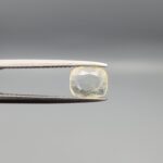 "Natural unheated Yellow Sapphire Pukhraj gemstone 1.25 carat cushion cut from Sri Lanka Ceylon held in tweezers showing pale ivory-yellow color and natural inclusions"