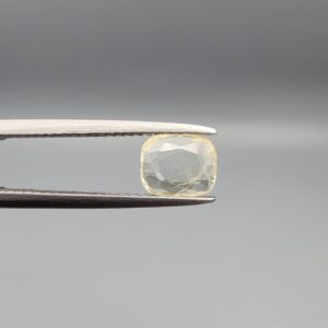 "Natural unheated Yellow Sapphire Pukhraj gemstone 1.25 carat cushion cut from Sri Lanka Ceylon held in tweezers showing pale ivory-yellow color and natural inclusions"