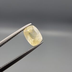 "Natural unheated Yellow Sapphire Pukhraj gemstone 2.59 carat cushion cut from Sri Lanka Ceylon held in tweezers showing silky natural inclusions and soft yellow color"