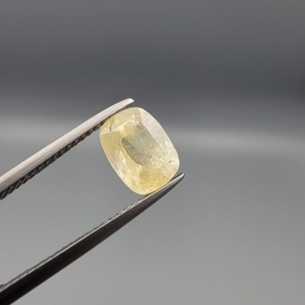 "Natural unheated Yellow Sapphire Pukhraj gemstone 2.59 carat cushion cut from Sri Lanka Ceylon held in tweezers showing silky natural inclusions and soft yellow color"