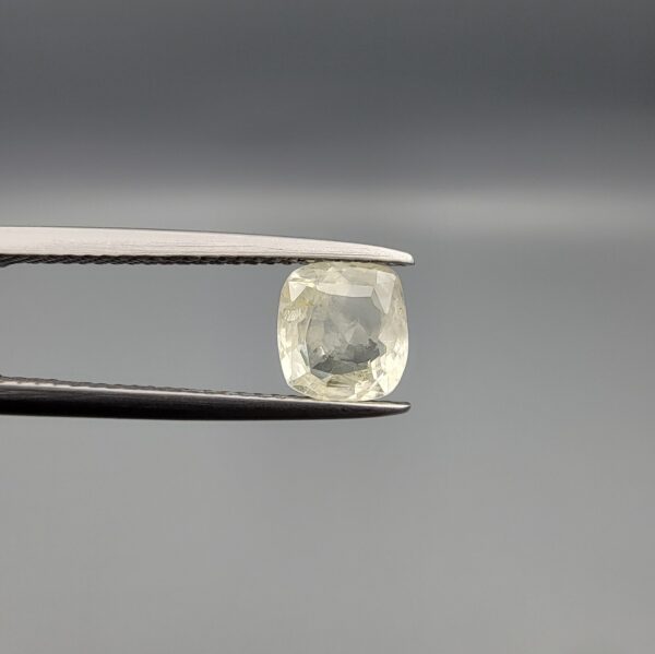 "Natural unheated Yellow Sapphire Pukhraj gemstone 1.46 carat cushion cut from Sri Lanka Ceylon held in tweezers showing pale near-colorless tone and natural inclusions"