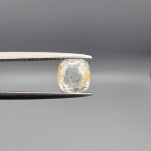 "Natural unheated Yellow Sapphire Pukhraj gemstone 1.97 carat cushion cut from Sri Lanka Ceylon held in tweezers showing near-colorless body with golden edge coloring"