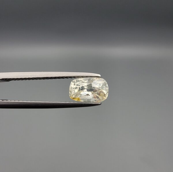 "Natural unheated Yellow Sapphire Pukhraj gemstone 1.66 carat elongated cushion cut from Sri Lanka Ceylon held in tweezers showing pale color with yellow patch and natural inclusions"