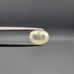 Natural unheated Yellow Sapphire Pukhraj gemstone 2.25 carat oval cut from Sri Lanka Ceylon held in tweezers showing pale ivory tone and natural inclusions