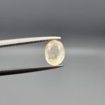 "Natural unheated Yellow Sapphire Pukhraj gemstone 1.53 carat oval cut from Sri Lanka Ceylon held in tweezers showing pale yellow color and natural inclusions"