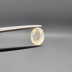 "Natural unheated Yellow Sapphire Pukhraj gemstone 1.53 carat oval cut from Sri Lanka Ceylon held in tweezers showing pale yellow color and natural inclusions"