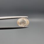 "Natural unheated Yellow Sapphire Pukhraj gemstone 2.58 carat oval cut from Sri Lanka Ceylon held in tweezers showing peachy-cream tone and natural inclusions"